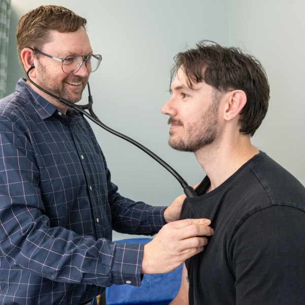 A doctor listening to a patient's heartbeat with a stethoscope